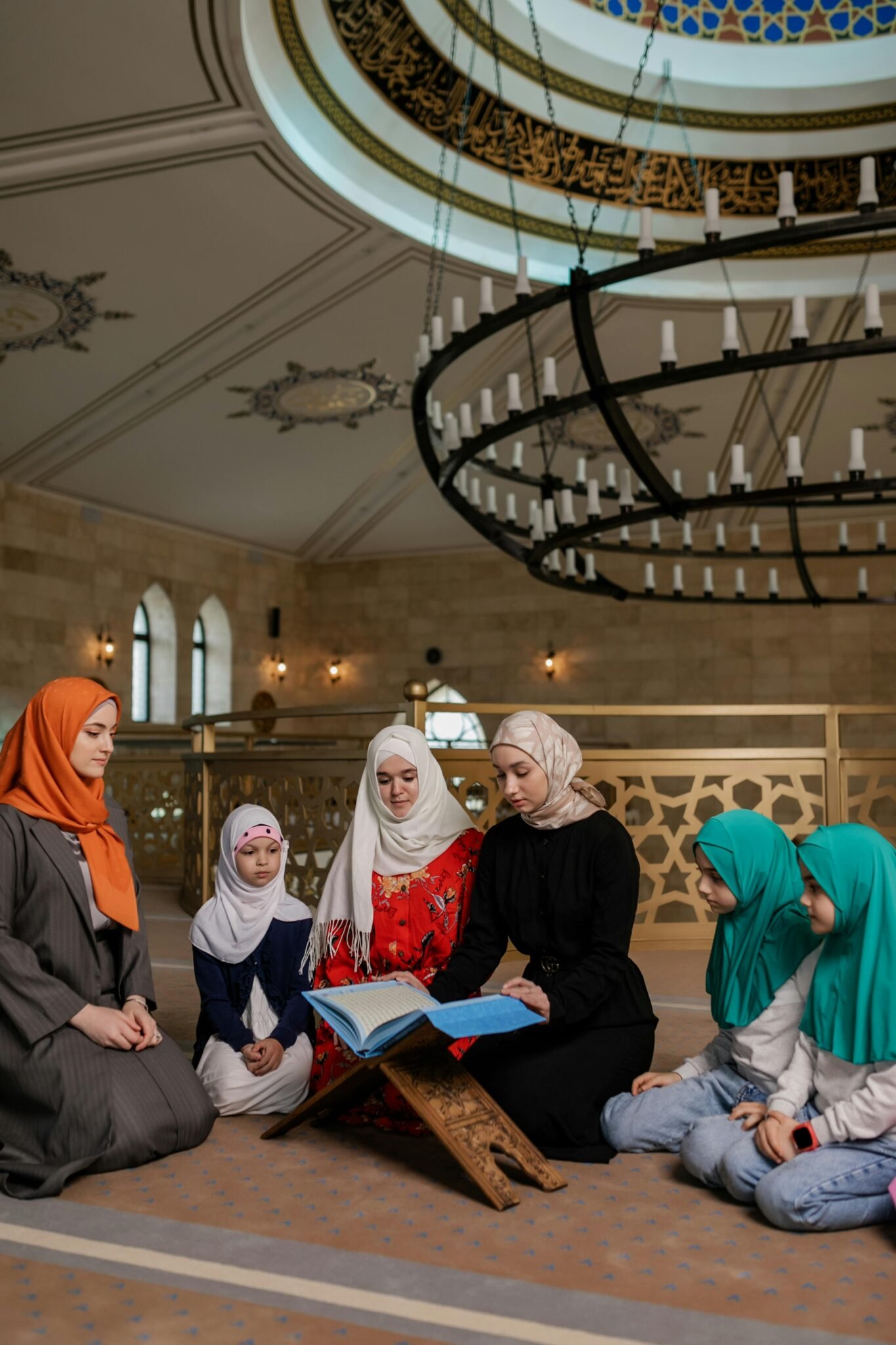 A Muslim family, including women and girls, gather for prayer in a beautifully adorned mosque.